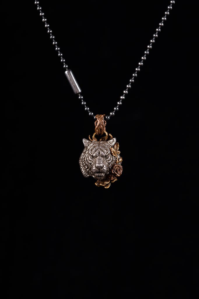 Detailed tiger pendant with floral design on a silver bead chain.